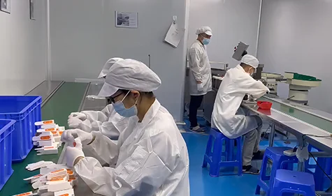 Workers handling individual packs at a packaging table