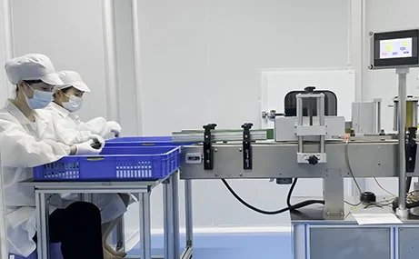 Gloved workers handling small product components beside a workbench